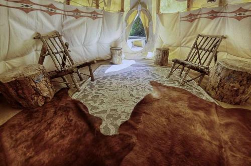 a room with two wooden chairs and a rug at Secluded Riverfront Tipi Retreat Surrounded by Pines in Garden Valley Idaho in Crouch