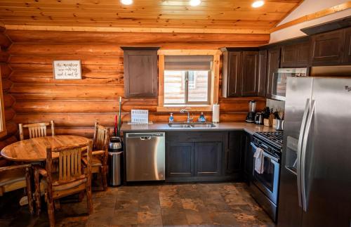 a kitchen with a table and a refrigerator at Luxury Pet-Friendly 1-Bedroom Log Cabin in Bonners Ferry with Full Kitchen and Wi-Fi in Bonners Ferry