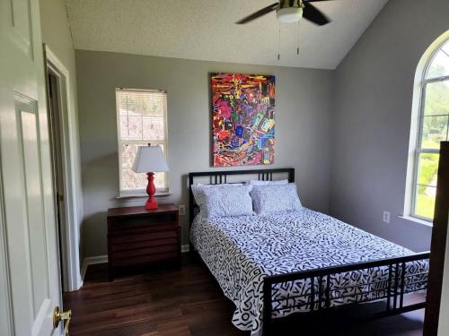 ein Schlafzimmer mit einem Bett und einem Gemälde an der Wand in der Unterkunft Quaint Cottage with Covered Dock on the Pond and Walking Trails in Georgia in Midway
