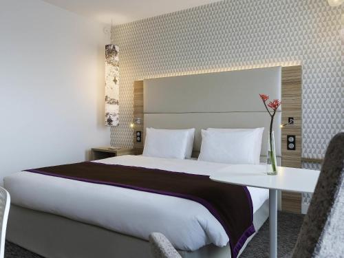 a hotel room with a large bed and a table at Mercure Paris Orly Rungis Aéroport in Rungis