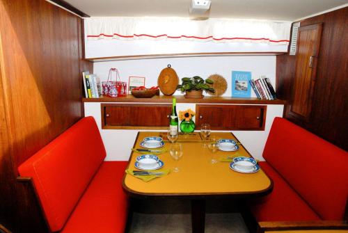a table with two red chairs and a yellow table with glasses at Unique Yacht Rental in a Peaceful Setting on Damariscotta River, Maine in Newcastle