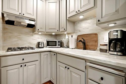 a white kitchen with white cabinets and a microwave at Inspiring Cottage Rental for a Vacation in California Wine Country in Lockeford