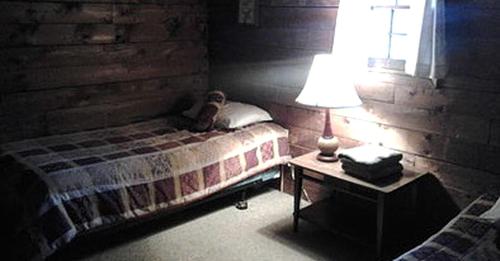 a bedroom with a bed and a lamp on a table at Simple Cabin Camping for Families in the Catskills of Upstate New York in Big Indian