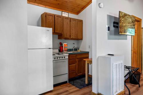 a kitchen with a white refrigerator and wooden cabinets at Charming Cabin with Spa and Mountain Views in Sevierville, Tennessee in Pinnacle