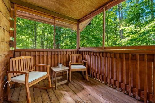 a screened in porch with two chairs and a table at Charming Cabin with Spa and Mountain Views in Sevierville, Tennessee in Pinnacle