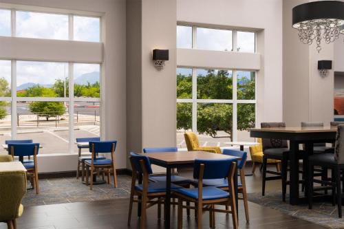 a dining room with blue chairs and a table and windows at Hampton Inn & Suites Albuquerque North/I-25 in Albuquerque