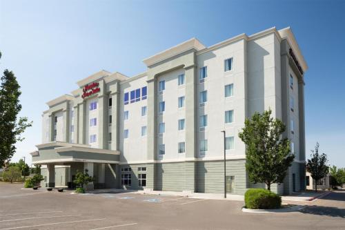 a large white hotel building with a parking lot at Hampton Inn & Suites Albuquerque North/I-25 in Albuquerque