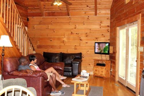 deux personnes assises sur un canapé en cuir dans un salon dans l'établissement Secluded Cabin Rental near Watoga State Park in West Virginia, à Hico