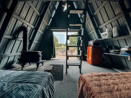 - une chambre avec une cheminée, un lit et une échelle dans l'établissement Rustic A-Frame Glamper near Nashville with Memory Foam Beds, Fire Pit & Country Breakfast, à Lebanon