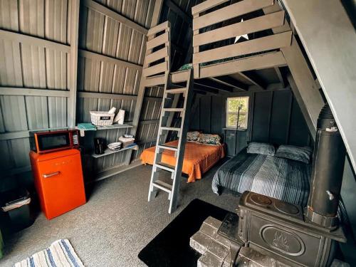 une chambre avec un lit superposé et une échelle dans l'établissement Rustic A-Frame Glamper near Nashville with Memory Foam Beds, Fire Pit & Country Breakfast, à Lebanon