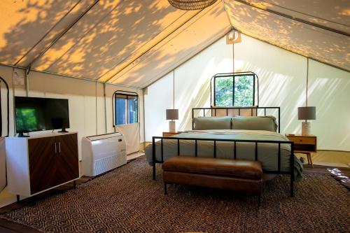 a bedroom with a bed and a tv in a tent at Stunning Tented Cabin with Fire Pit in Des Moines, Iowa in Marquisville
