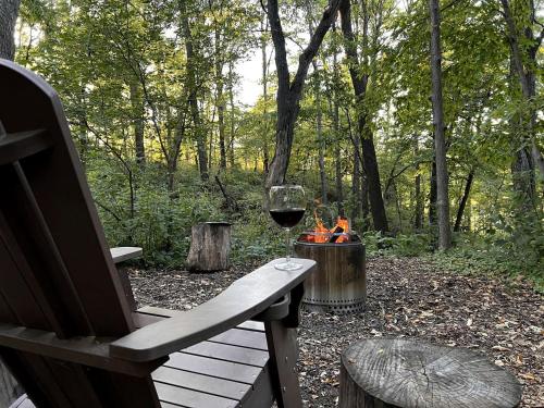 a bench with a glass of wine and a fire place at Stunning Tented Cabin with Fire Pit in Des Moines, Iowa in Marquisville