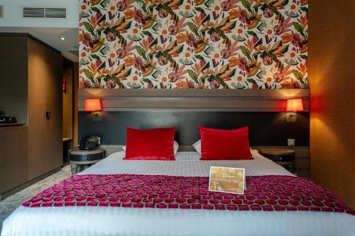 a bedroom with a large bed with red pillows at Van Der Valk Sélys Liège Hotel & Spa in Liège