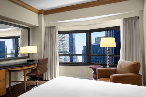 a hotel room with a bed and a desk and chair at New York Hilton Midtown in New York