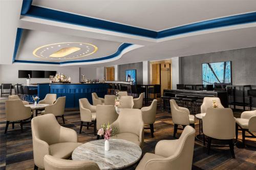 a restaurant with tables and chairs and a piano at New York Hilton Midtown in New York