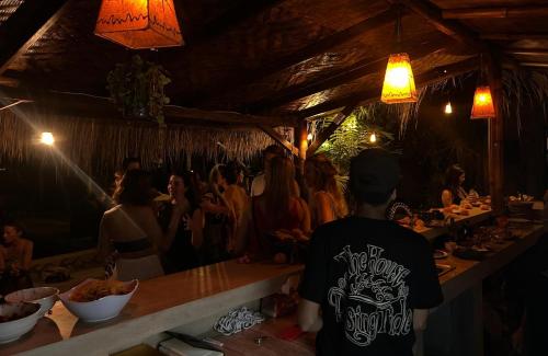 a group of people standing around a bar at The House of The Rising Tide in Mantaak