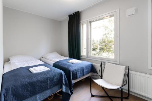 a bedroom with two beds and a chair and a window at Newly renovated large family apartment, parking, sauna, balcony in Jyväskylä