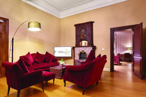 a living room with red chairs and a fireplace at Van Der Valk Sélys Liège Hotel & Spa in Liège