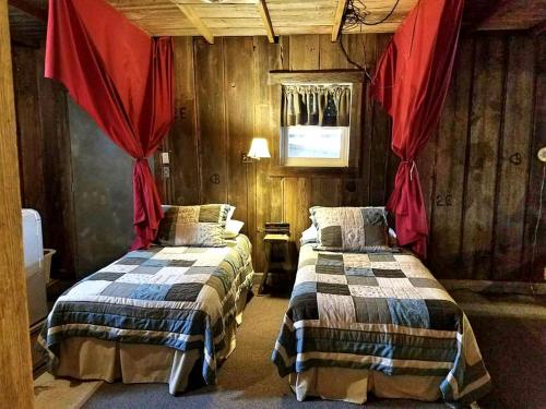Ce lit se trouve dans un dortoir doté de murs en bois et de rideaux rouges. dans l'établissement Rustic Barn Rental for a Rural Vacation near Des Moines, Iowa, à Montezuma
