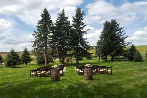 eine Gruppe von Tischen und Stühlen auf einem Feld mit Bäumen in der Unterkunft Rustic Barn Rental for a Rural Vacation near Des Moines, Iowa in Montezuma