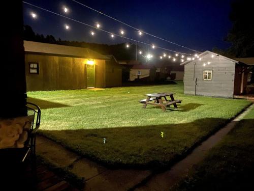 una mesa de picnic en un patio por la noche con luces en Cozy Tiny Cabin 8 in Rapid City, SD, en Hill City