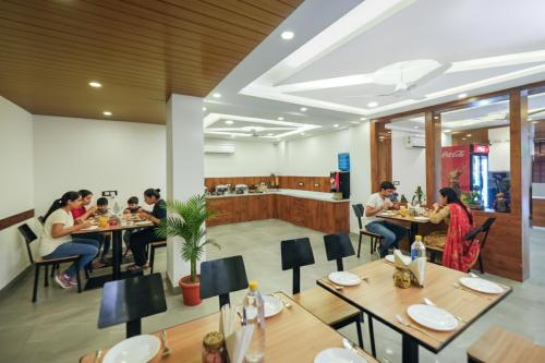 a group of people sitting at tables in a restaurant at FabHotel Golf Inn - Business-Friendly Stay near Golf Course Road, Cyberhub & Metro in Gurgaon