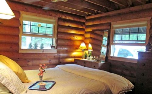 ein Schlafzimmer mit einem Bett in einem Zimmer mit Holzwänden in der Unterkunft Lovely Log Cabin with Spectacular Mountain Views in Brandon, Vermont in Pittsford