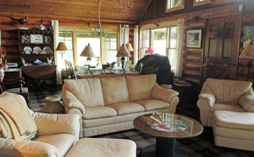 ein Wohnzimmer mit Sofa und Tisch in der Unterkunft Lovely Log Cabin with Spectacular Mountain Views in Brandon, Vermont in Pittsford