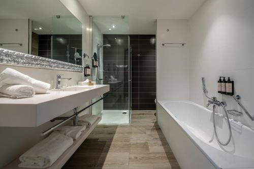 a bathroom with two sinks and a tub and a shower at Van Der Valk Sélys Liège Hotel & Spa in Liège