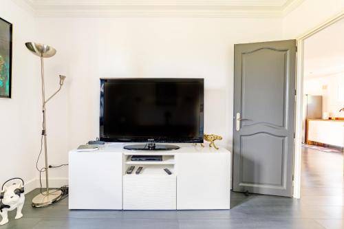 a living room with a flat screen tv on a white cabinet at Apartment with pool and garden in Taradeau