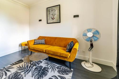 a living room with a yellow couch and a fan at Apartment with pool and garden in Taradeau