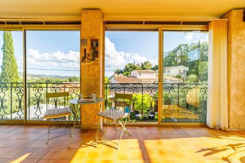 a balcony with a table and chairs and large windows at Apartment with pool and garden in Taradeau