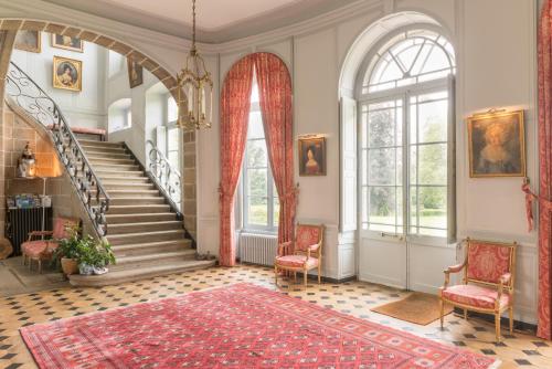 a living room with a staircase and a red rug at Château de Boucéel - Mont Saint Michel in Vergoncey