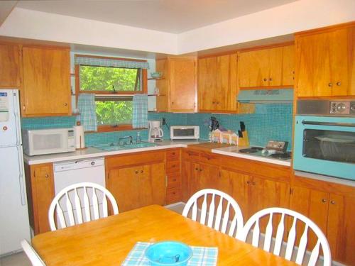 a kitchen with wooden cabinets and a table with chairs at Peaceful Private Cabin on Crystal Lake near Elk Mountain, Pennsylvania in Dundaff