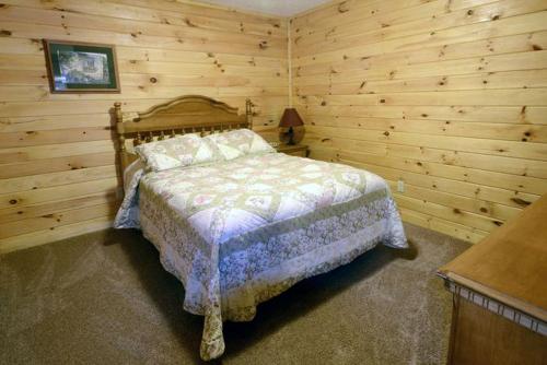 a bedroom with a bed in a room with wooden walls at Charming Log Cabin with a Fire Pit in the Woods near Lake Logan in Ohio in Cedar Grove