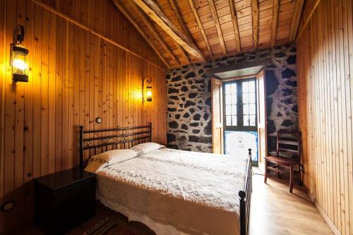 a bedroom with a bed in a room with wooden walls at Villa 4 Seasons in São Roque do Pico