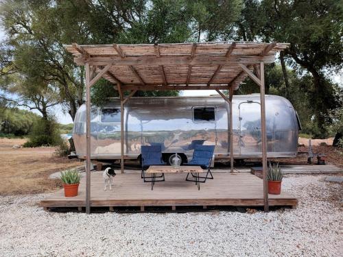 ein Wohnmobil mit einer Terrasse mit Stühlen und einem Hund darauf in der Unterkunft Airstream Oasis: Unique Retreat near Andalucia's Best Beaches and Nature Haven! in El Soto