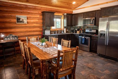 a kitchen with a wooden table and a refrigerator at Spacious Luxury Cabin with Bunk Room & Nature Trail Access near Bonners Ferry, Idaho in Bonners Ferry