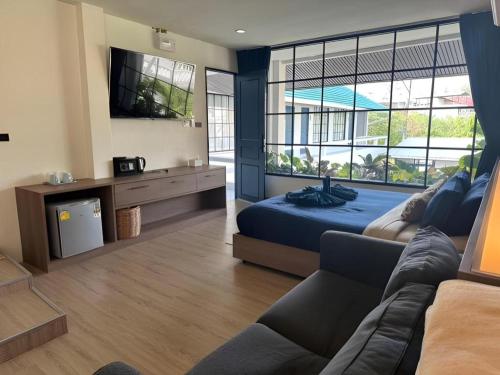 a bedroom with a bed and a tv and a couch at Calm Kamala Phuket in Kamala Beach