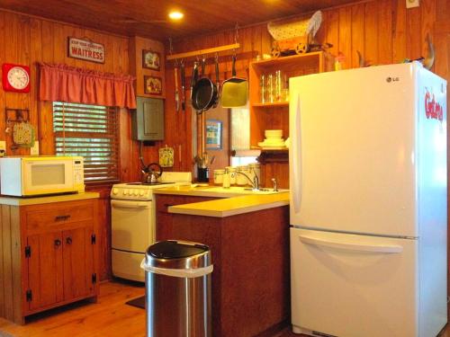 Una cocina con refrigerador blanco y gabinetes de madera. en Lakefront Weekend Getaway with a Private Dock near the Ocala National Forest, Florida, en Orange Springs