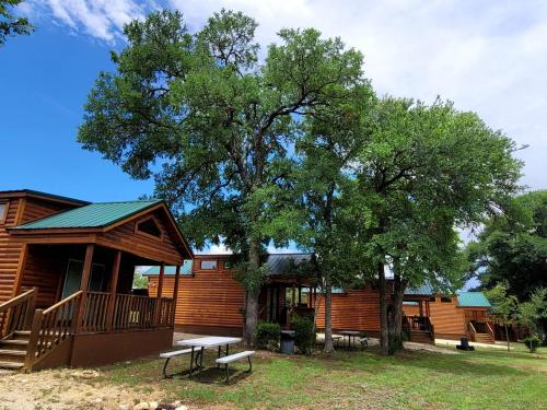 a log cabin with a bench and a tree at Comfortable Cabin Rental with Pool Access near San Antonio, Texas in Pipe Creek