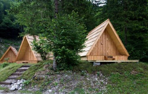 a group of wooden huts in a forest at Unique A-Frame Cabin Rentals for a Vacation near Bovec, Slovenia in Soča