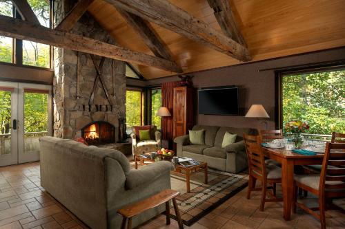 a living room with a stone fireplace and a table at Riverfront Cabin Rental with a Private Beach on Youghiogheny River near Pittsburgh, Pennsylvania in Confluence