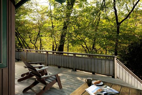 a porch with two chairs and a table on a deck at Riverfront Cabin Rental with a Private Beach on Youghiogheny River near Pittsburgh, Pennsylvania in Confluence