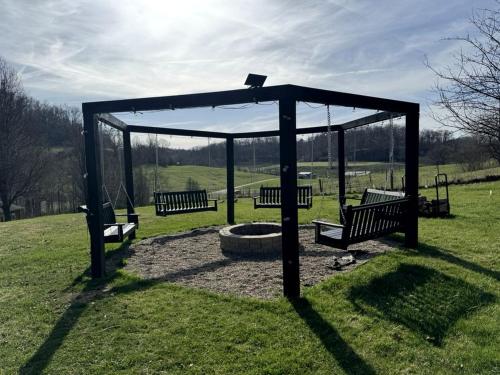 a group of benches sitting in a park at 16 Guests | Ponds | Hot Tub | Game Room | Trails in Sarahsville in Senecaville