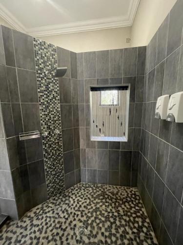 a bathroom with a shower with a window at Bush Lovers Lodge in Modimolle
