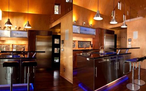 two pictures of a kitchen with a bar with stools at Unique Cottage Rental with Sublime Views Nestled on Damariscotta Lake in Maine in Jefferson