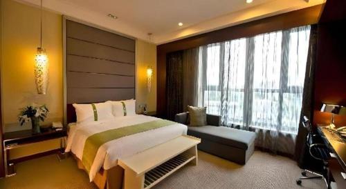 una camera da letto con un letto grande e una grande finestra di GreenTree Inn Changshu South HaiYu Road Pedestrian Street Business Hotel a Suzhou