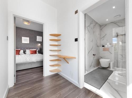 ein weißes Schlafzimmer mit einem Bett und einem Badezimmer in der Unterkunft Brand New Luxurious 3bed House in Northfleet