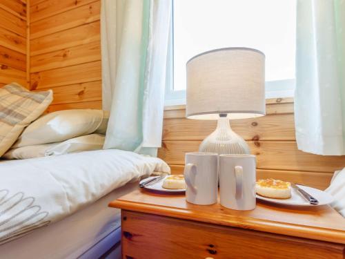 a table with two cups and a lamp on a bed at 2 Bed in Loch Leven 82297 in Kinross